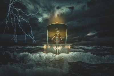 Digital composite image of illuminated light by sea against sky