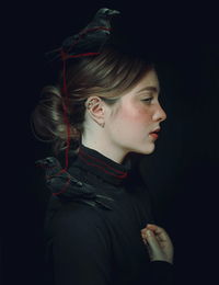 Side view of woman with bird against black background