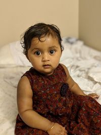 Close-up portrait of cute baby girl on bed