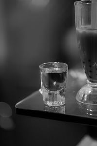 Close-up of shot glass next to bubble tea 