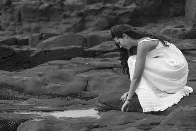 Side view of woman sitting on rock