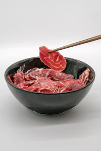 Close-up of meat in bowl against white background