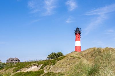 Lighthouse on field against blue sky