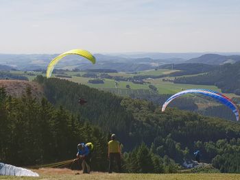 People in mid-air by mountains against sky