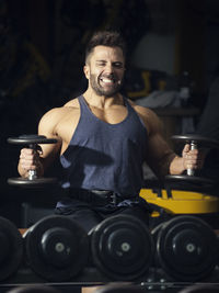 Close-up of muscular man holding dumbbell at gym