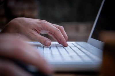 Close-up view of male hands working on laptop outside the house. a businessman works on  notebook 