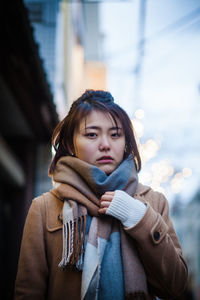 Portrait of young woman wearing warm clothing while standing in city