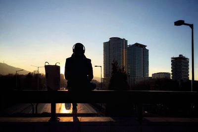 Silhouette man and buildings against clear sky