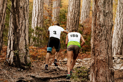 Rear view of men running in forest