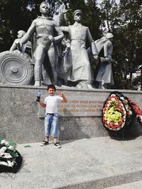 Full length of boy standing by statue