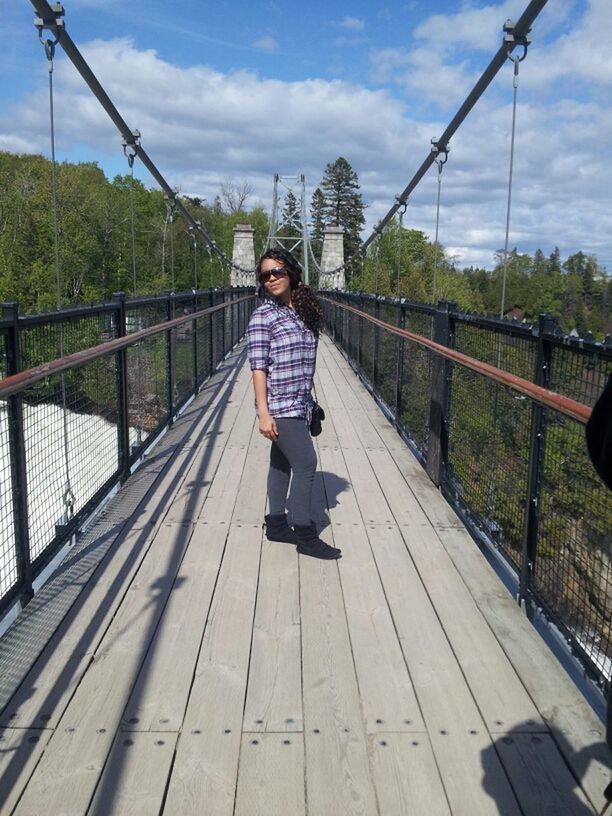 full length, lifestyles, casual clothing, person, leisure activity, railing, young adult, looking at camera, childhood, tree, sky, bridge - man made structure, smiling, portrait, elementary age, front view, young women, standing