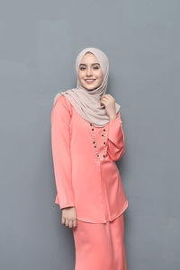 Portrait of smiling young woman standing against white background