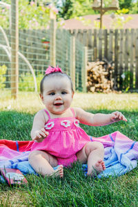 Portrait of cute baby girl sitting in yard