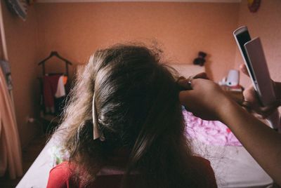 Rear view of woman using mobile phone at home