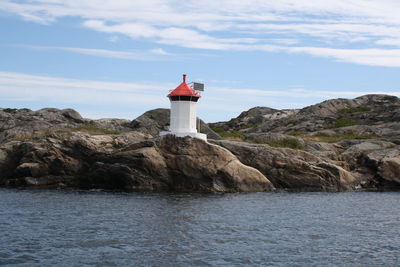 Lighthouse by sea against sky