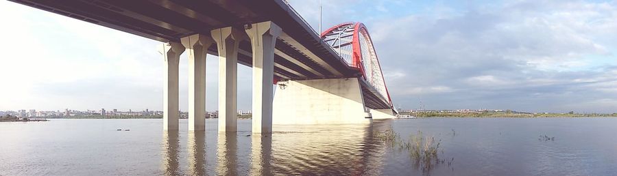 Bridge over river against cloudy sky