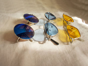 Three pairs of sunglasses yellow, blue and mirror glasses on a linen background. colored glasses 