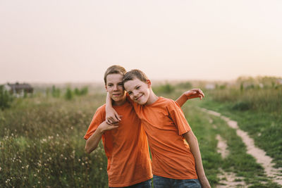 Funny twin brother boys playing outdoors on field at sunset.