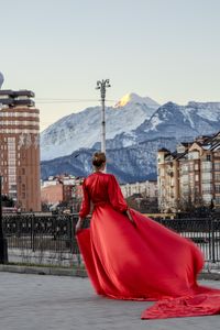 Rear view of woman in front of buildings against clear sky