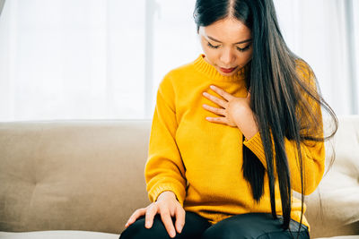 Young woman sitting on sofa at home