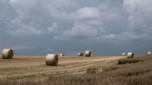 Hay bales on field against sky