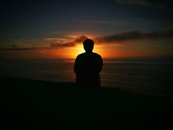 Silhouette man standing at beach against sky during sunset