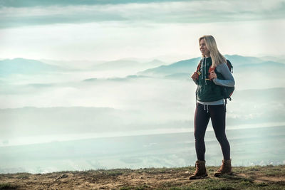 Happy woman tourist stay on green grass on peak of mountain and look on nice view. concept freedom.