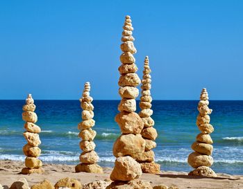 Stack of rocks on beach against clear blue sky