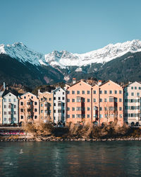 Buildings by mountains against clear sky during winter