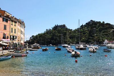 Boats moored in river against clear blue sky