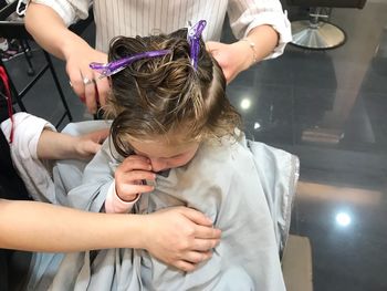 Hairdressers cutting girl hair in shop