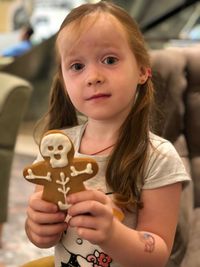 Close-up portrait of cute girl holding gingerbread man