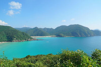 View of calm blue sea against mountain range