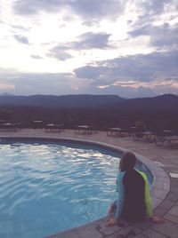 Rear view of man in swimming pool against sky