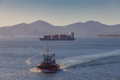 Container ship and tugboat in front of the port of piraeus, athens, greece