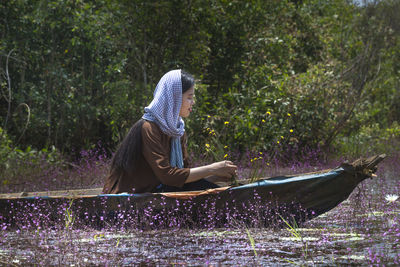 Woman in boat against trees