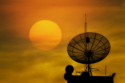 Silhouette of communications tower against sky during sunset