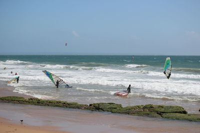 People windsurfing on sea against sky