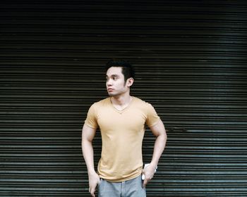 Young man standing against closed shutter