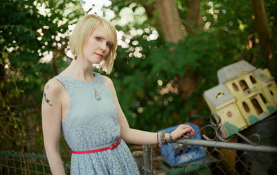 Portrait of woman standing by railing at yard