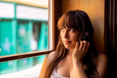 Young woman looking through window