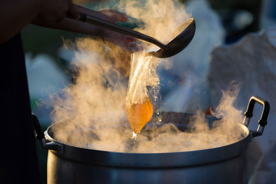 Cropped hands pouring drink in plastic bag at market stall