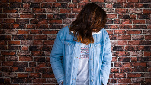 Woman standing against brick wall