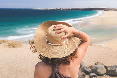 Midsection of woman wearing hat at beach