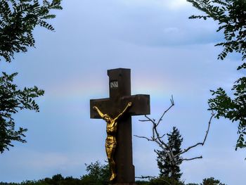 Low angle view of cross sculpture against sky