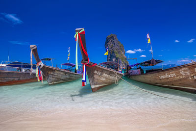 Boats moored in sea against blue sky