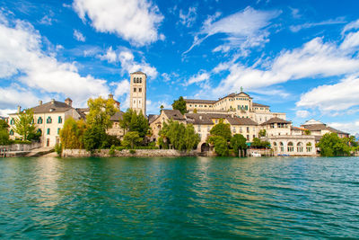 Isola san giulio inside orta's lake, piemonte, italy, from water surface with blue sky.