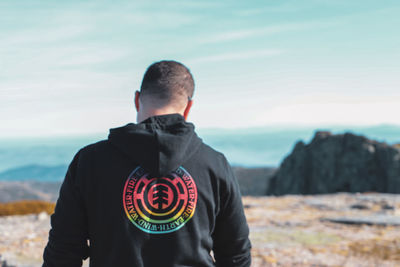 Rear view of man looking at sea against sky