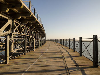 Footbridge over pier against clear sky