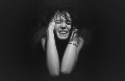 Depressed woman with head in hands sitting at darkroom